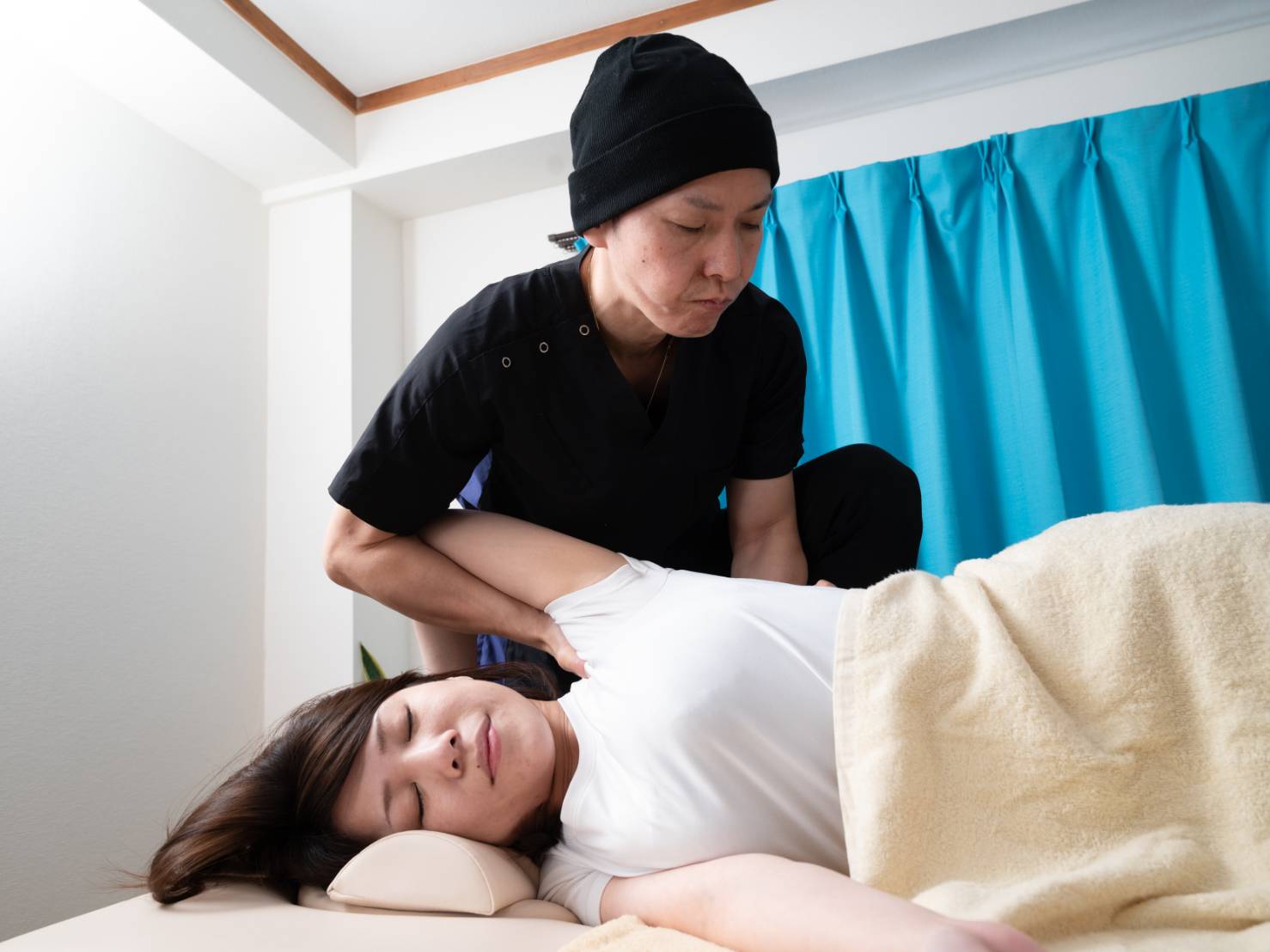 横向きの姿勢で肩まわりを丁寧に施術する様子